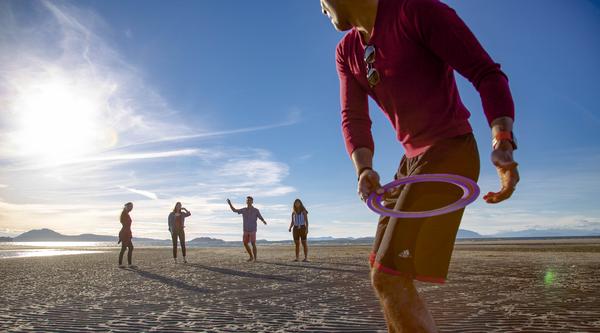 Students play frisbee at a beach