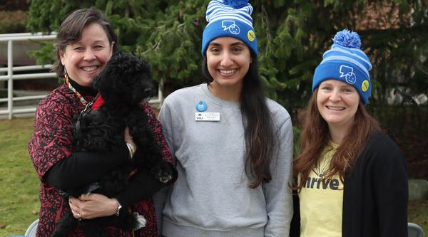 Three people pose, one of whom is holding a dog