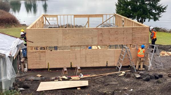 Students frame up a home with an ocean view in the background