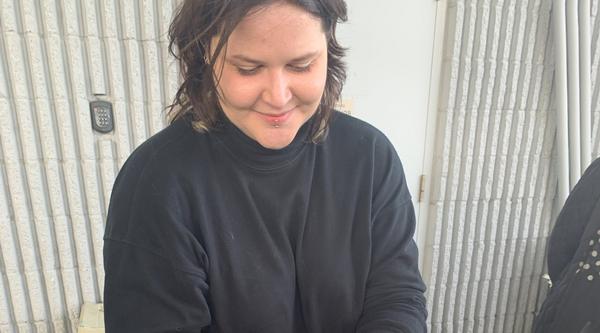 Chloe McLaughlin stands by a tank, holding an urchin.