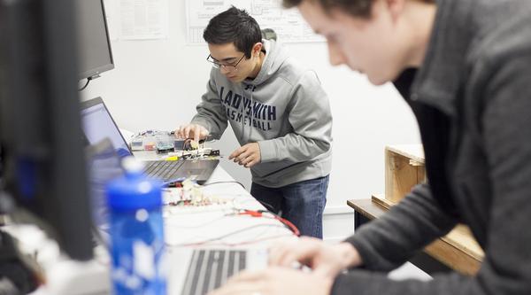 Two VIU Engineering students work on computer equipment in a lab.