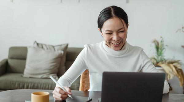 Women typing on a laptop with tablet next to her