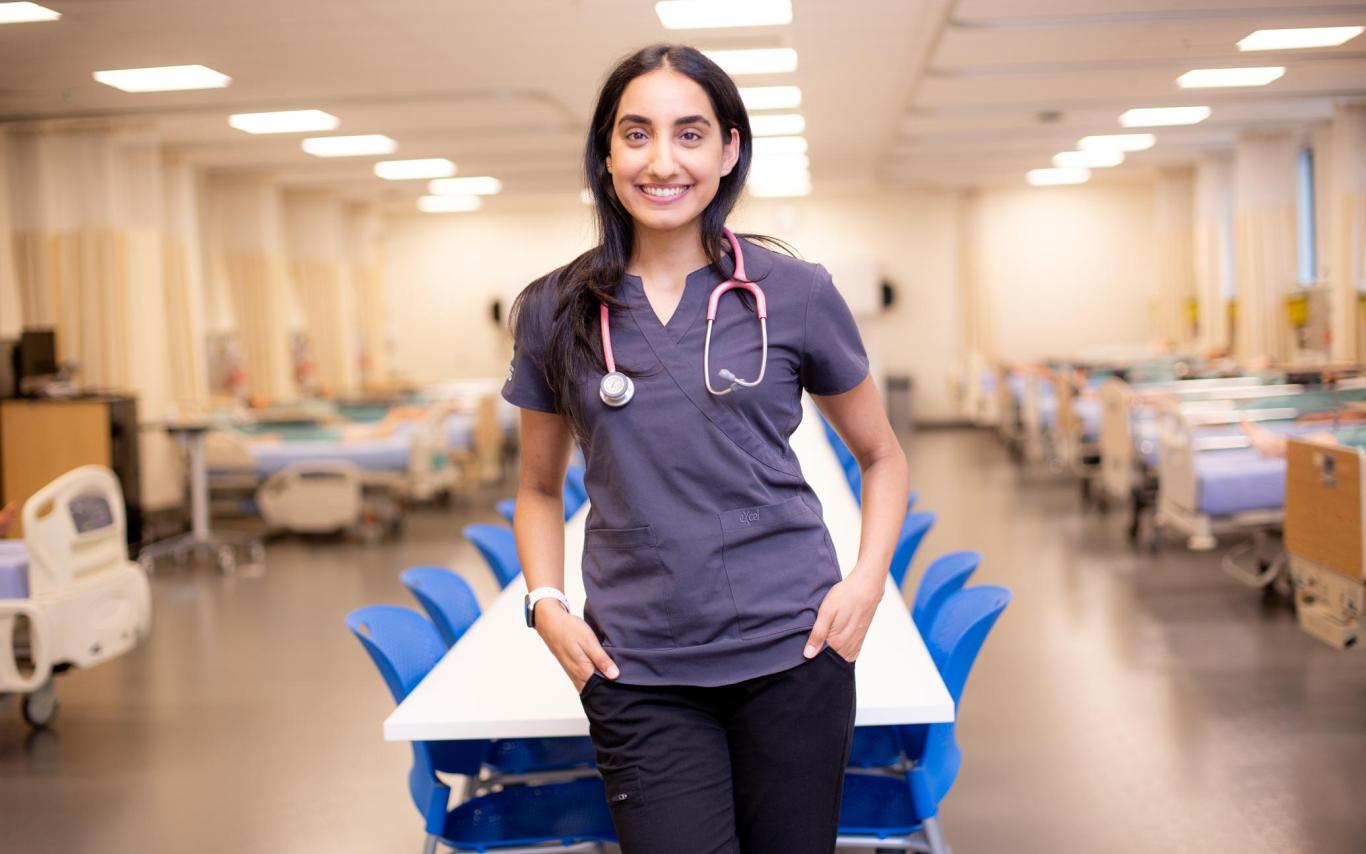 Ashley stands in VIU's nursing simulation lab, wearing scrubs and a stethoscope