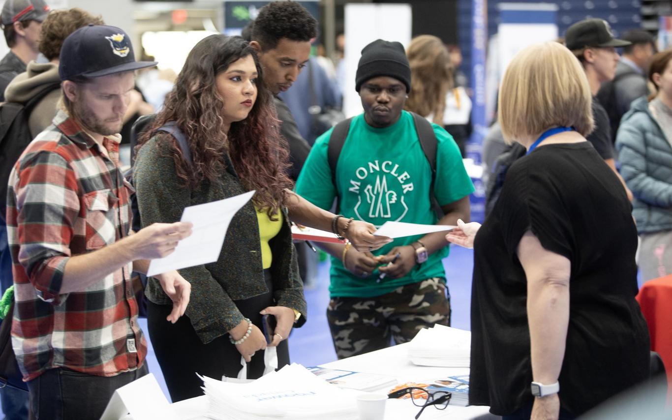 Three students interact with a vendor at the Career Fair