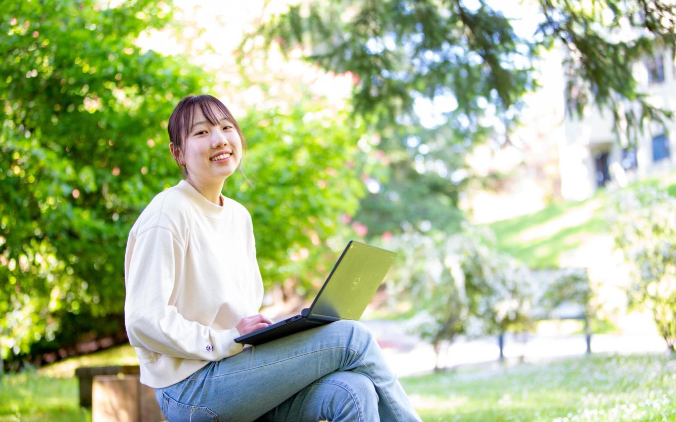 Student working on a laptop in nature