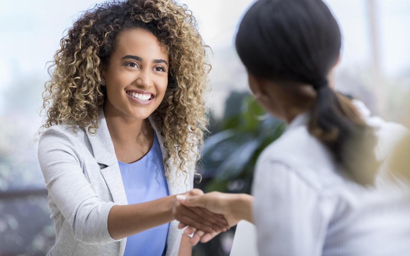 a woman shakes hands with another woman