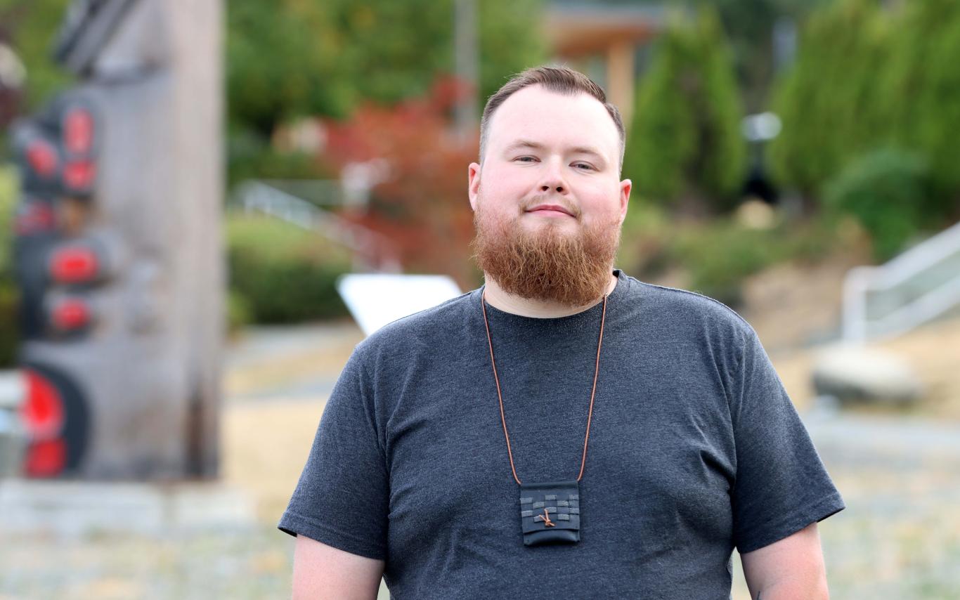 Portrait of Aaron Moore in front of totems at VIU Nanaimo campus