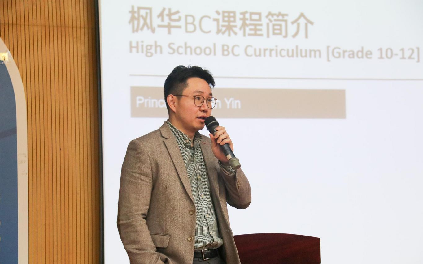 Brian Yin holds a microphone near a podium.