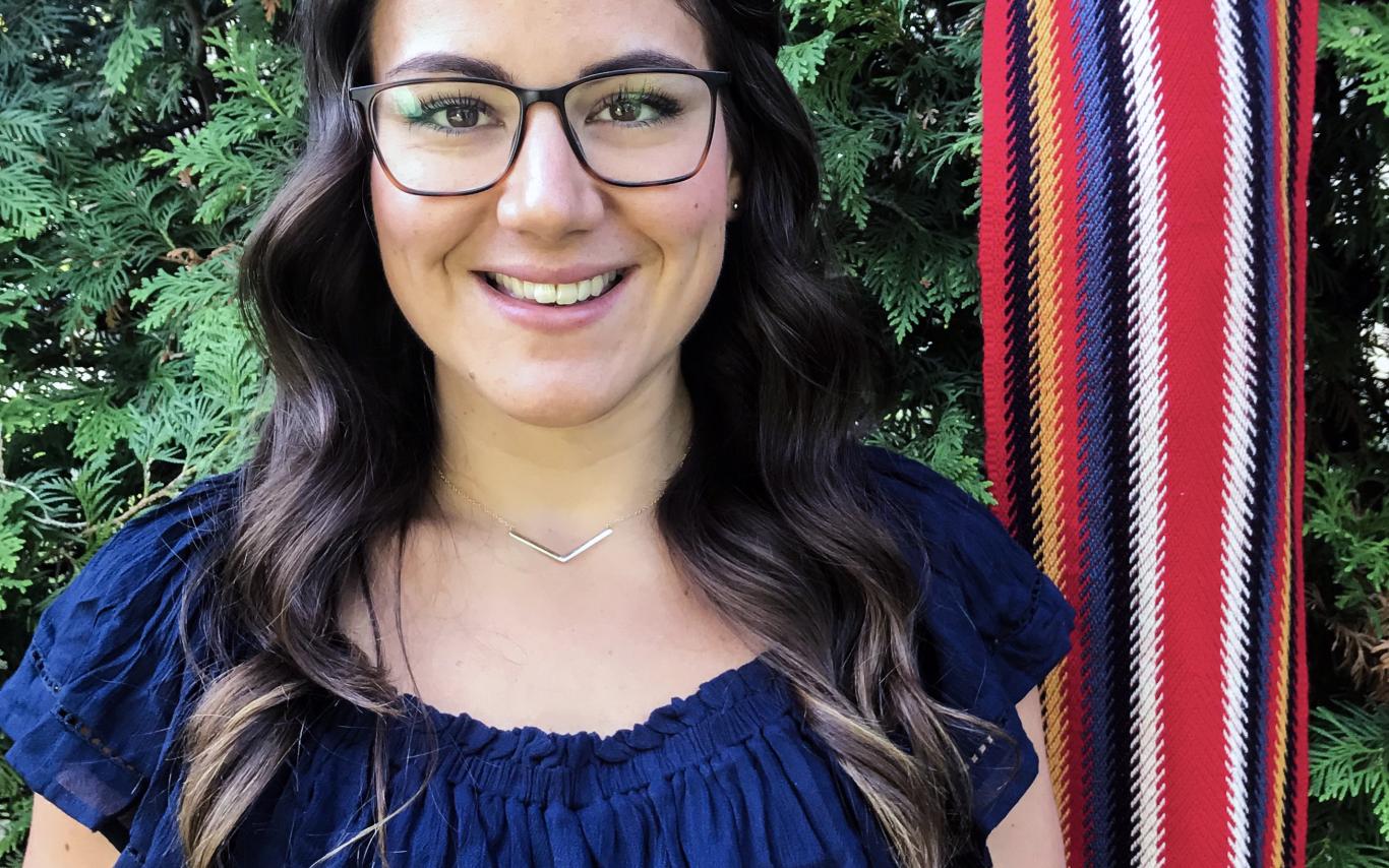 Cassidy Caron smiling with a Metis sash in background