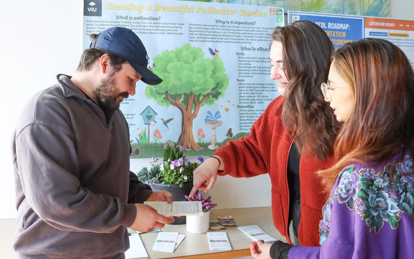 Three students next to a poster explaining research