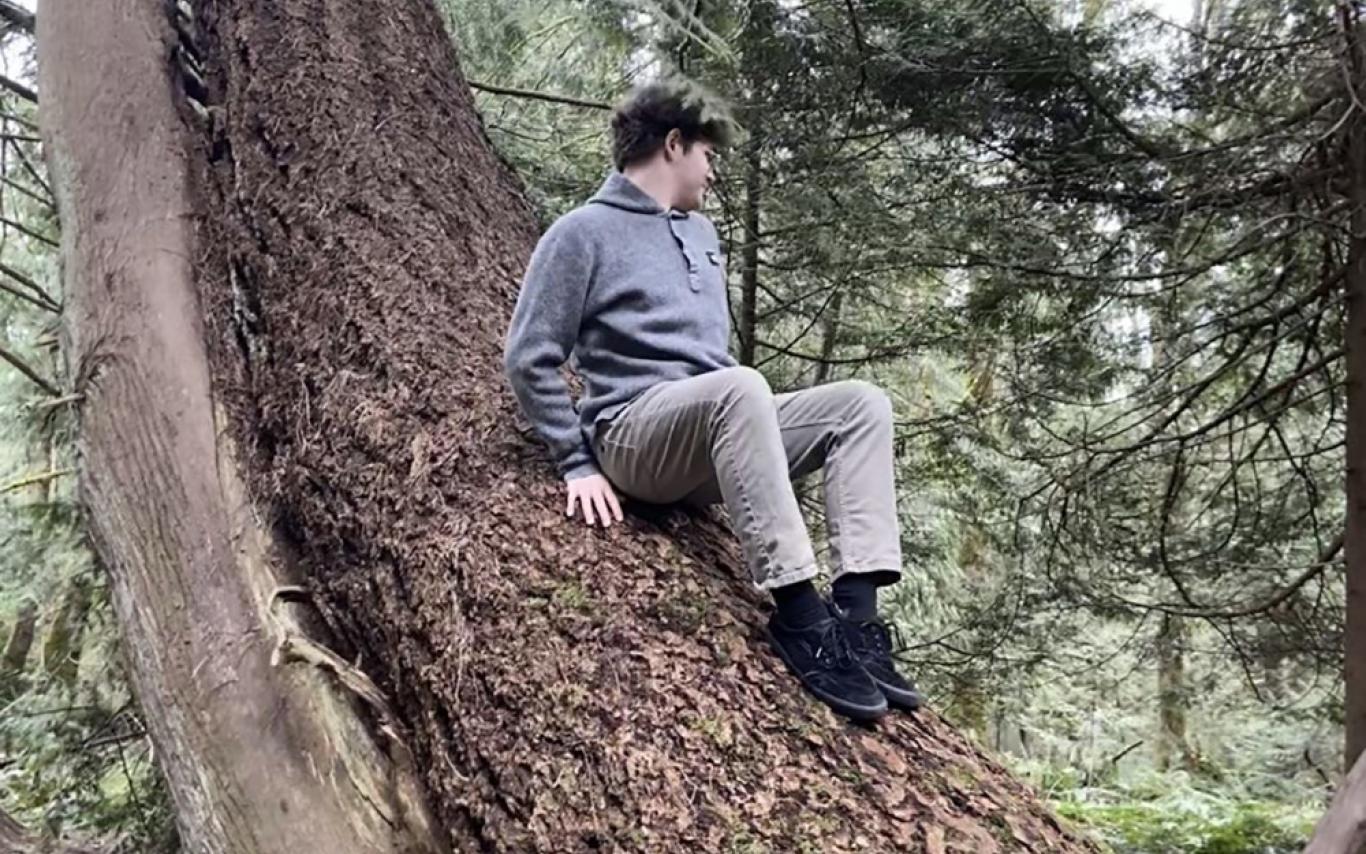 Ethan Hummel sits on a tree trunk.