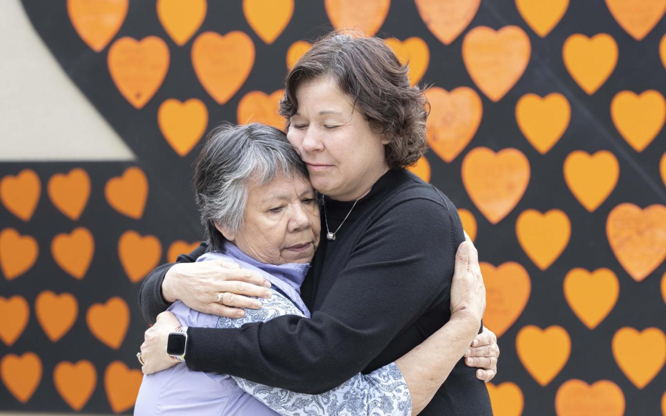 President Saucier and Auntie Geraldine hug in front of a wall of orange hearts
