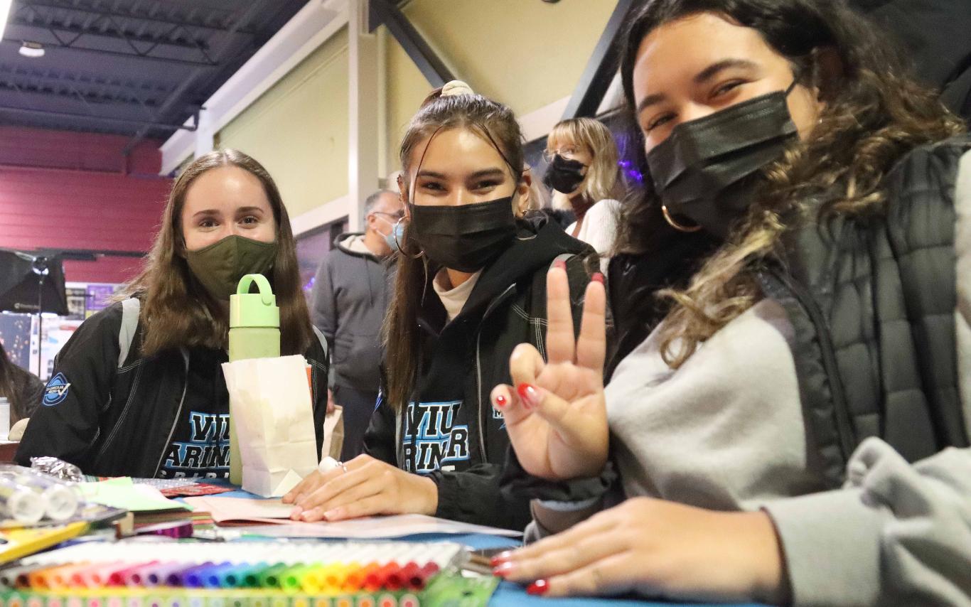 Three students sitting at a table, smiling for camera