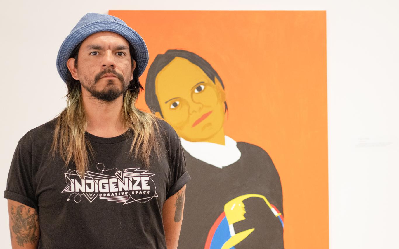 Atticus Mercredi stands in front of the painting of his mother.