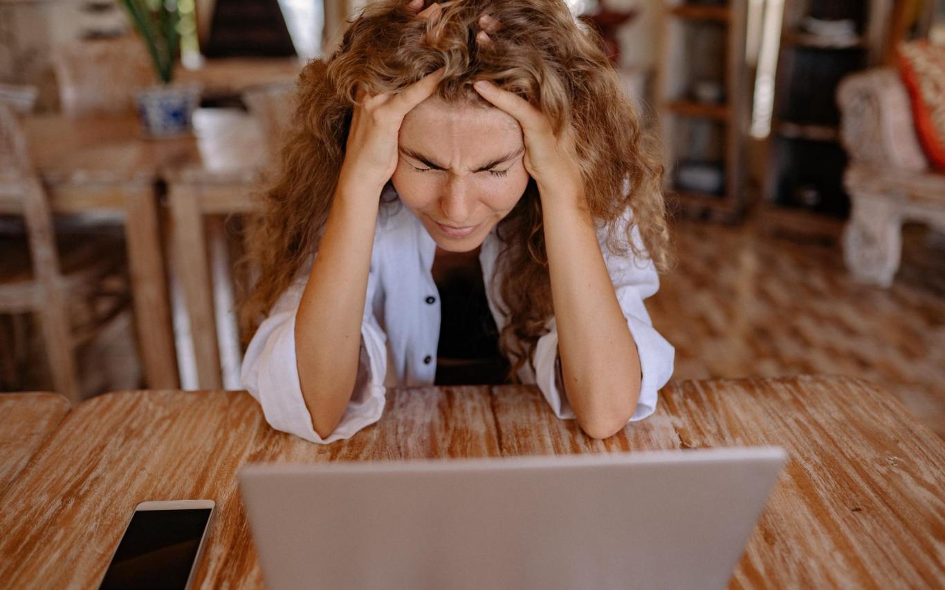 Woman stares at a laptop screen, head in her hands