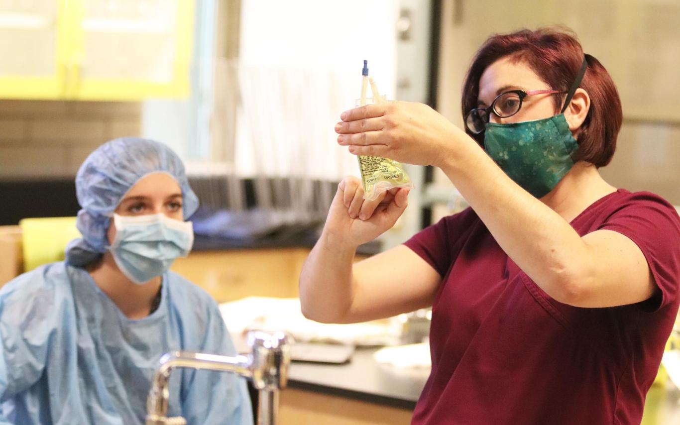 A student in a classroom watching an instructor fill a prescription bottle