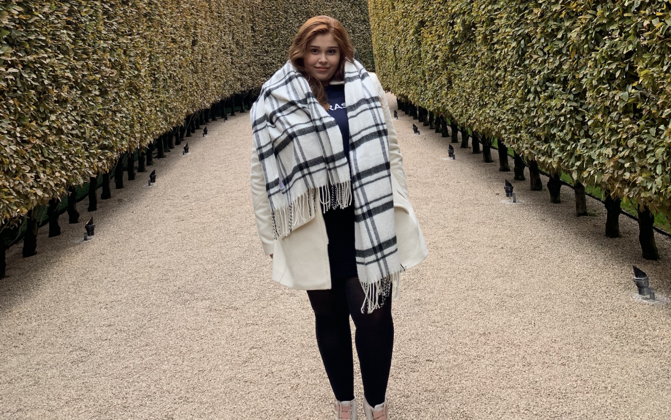 Gabrielle Hayashi Santos standing outside between two hedges looking at the camera 