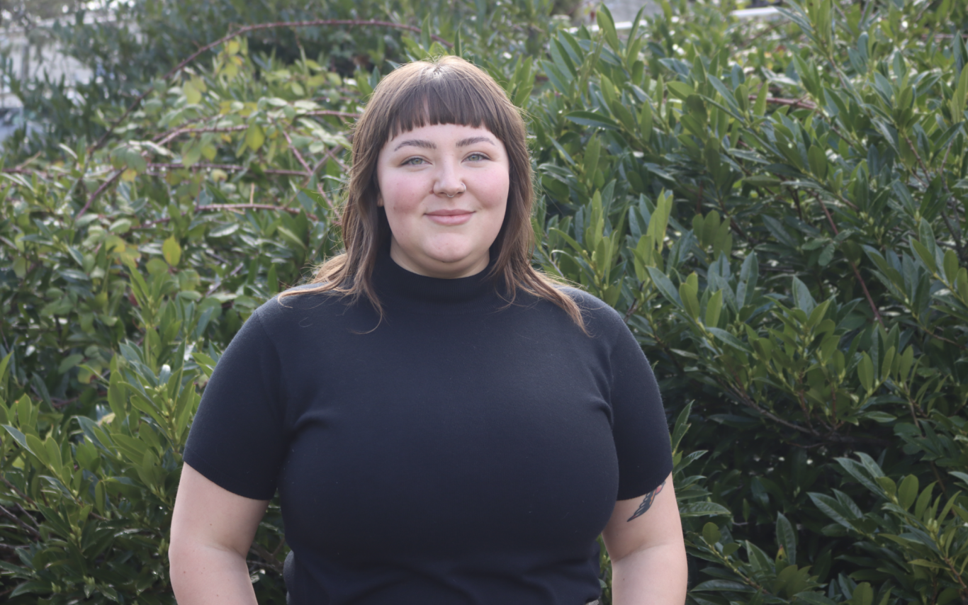 Sierra De Buysscher-Nailor standing smiling at the camera in front of a bush