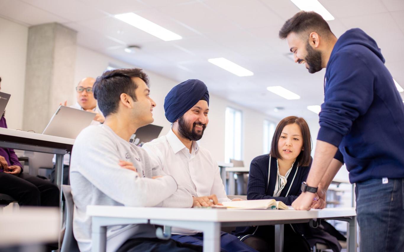 Four students interact around a desk