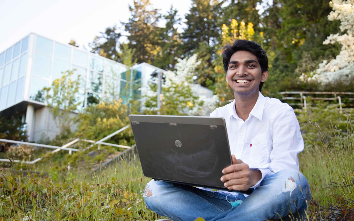 Student typing on laptop outside