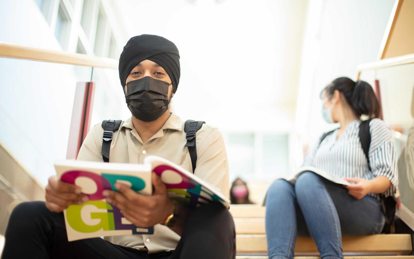 Student sitting on stairs with book