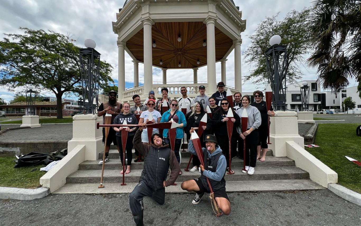 a group holding paddles poses for a photo