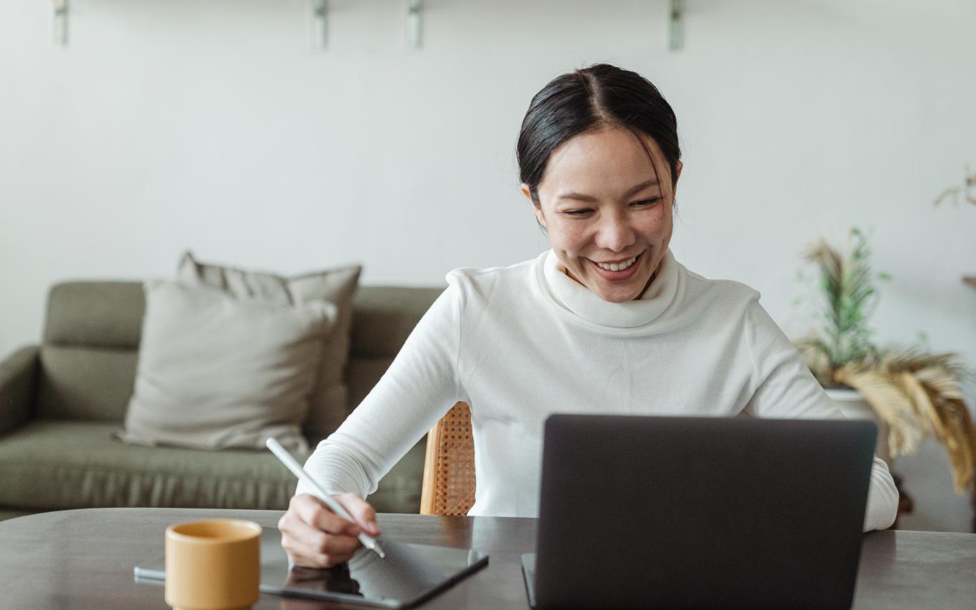 Women typing on a laptop with tablet next to her