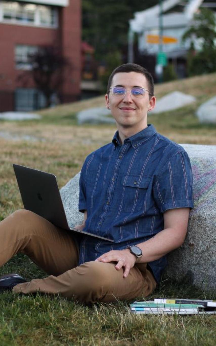 Portrait of spenser smith sitting with his back resting on a log
