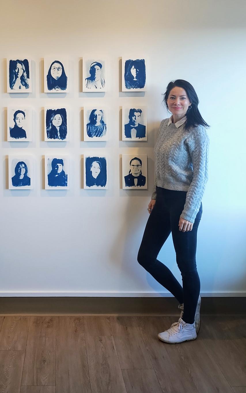 Tarah Dowling stands next to her exhibit, which includes 15 portraits and a headset to listen to the audio.